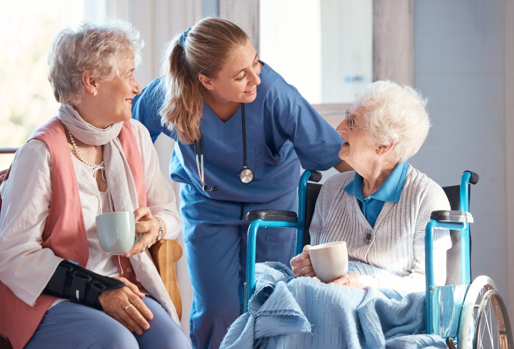 nurse offering help to two elderly residents